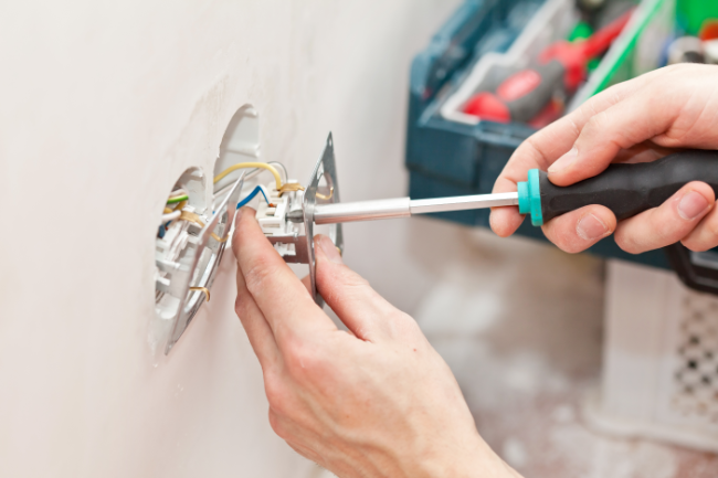 Person using a screwdriver on a wall plug