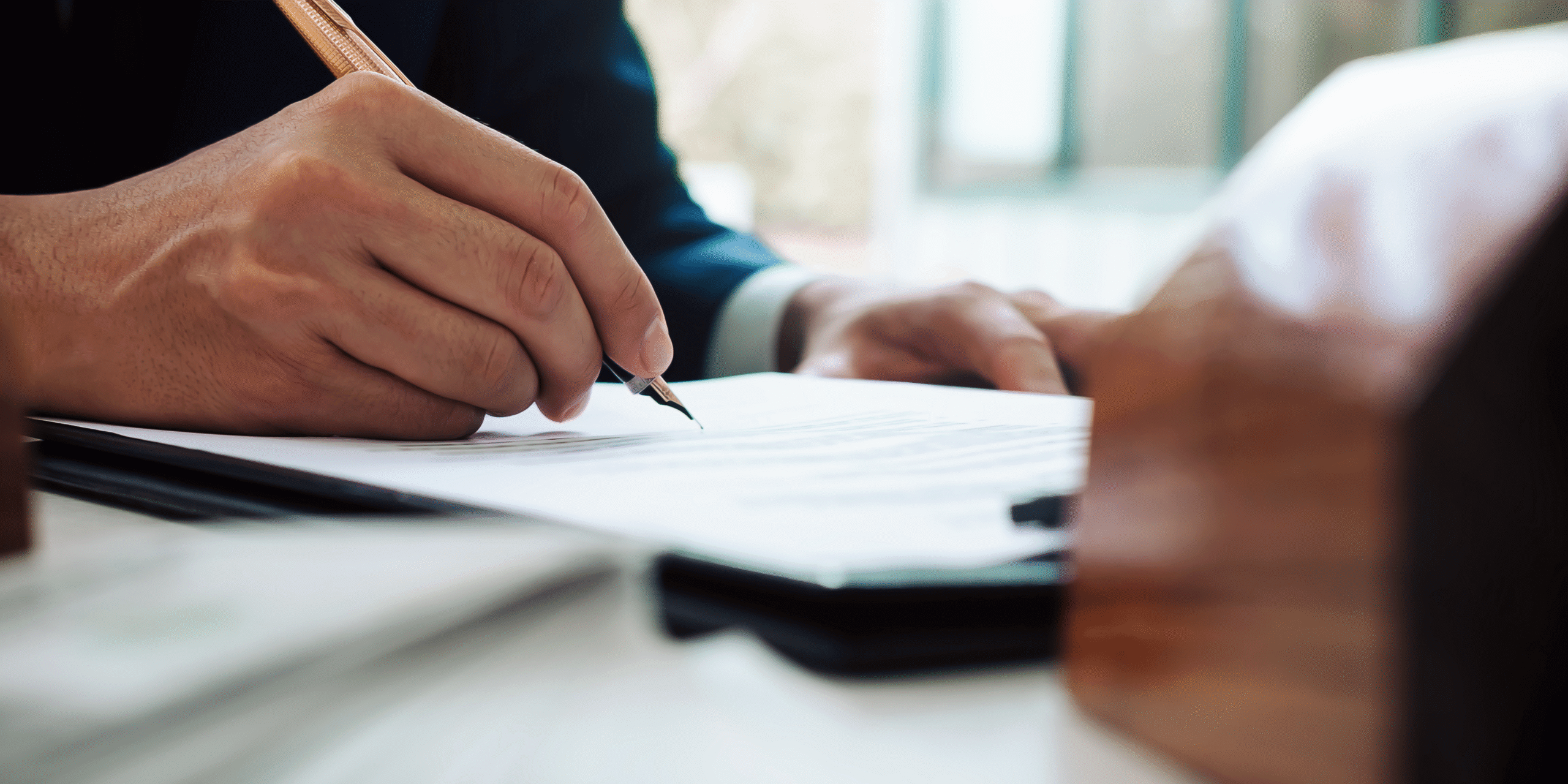 Close up of someone signing a document. 