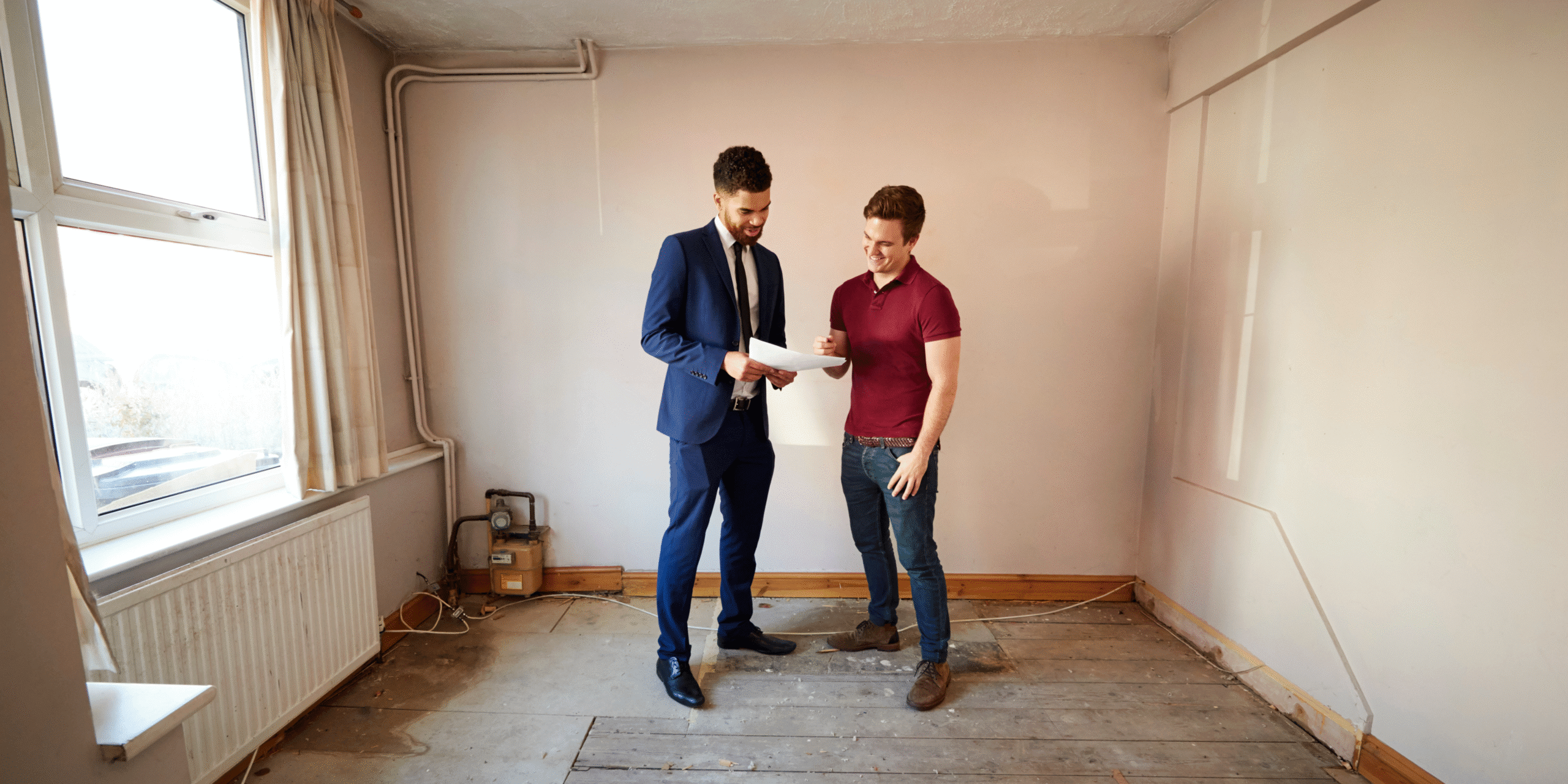 Two men discussing house plans and looking at a clipboard.