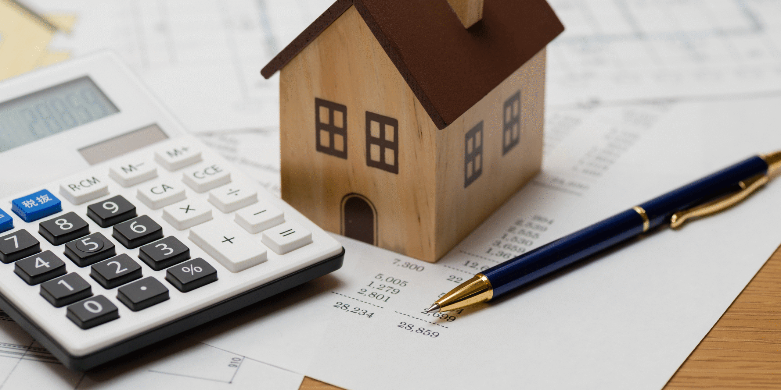 Paperwork and wooden house on desk.