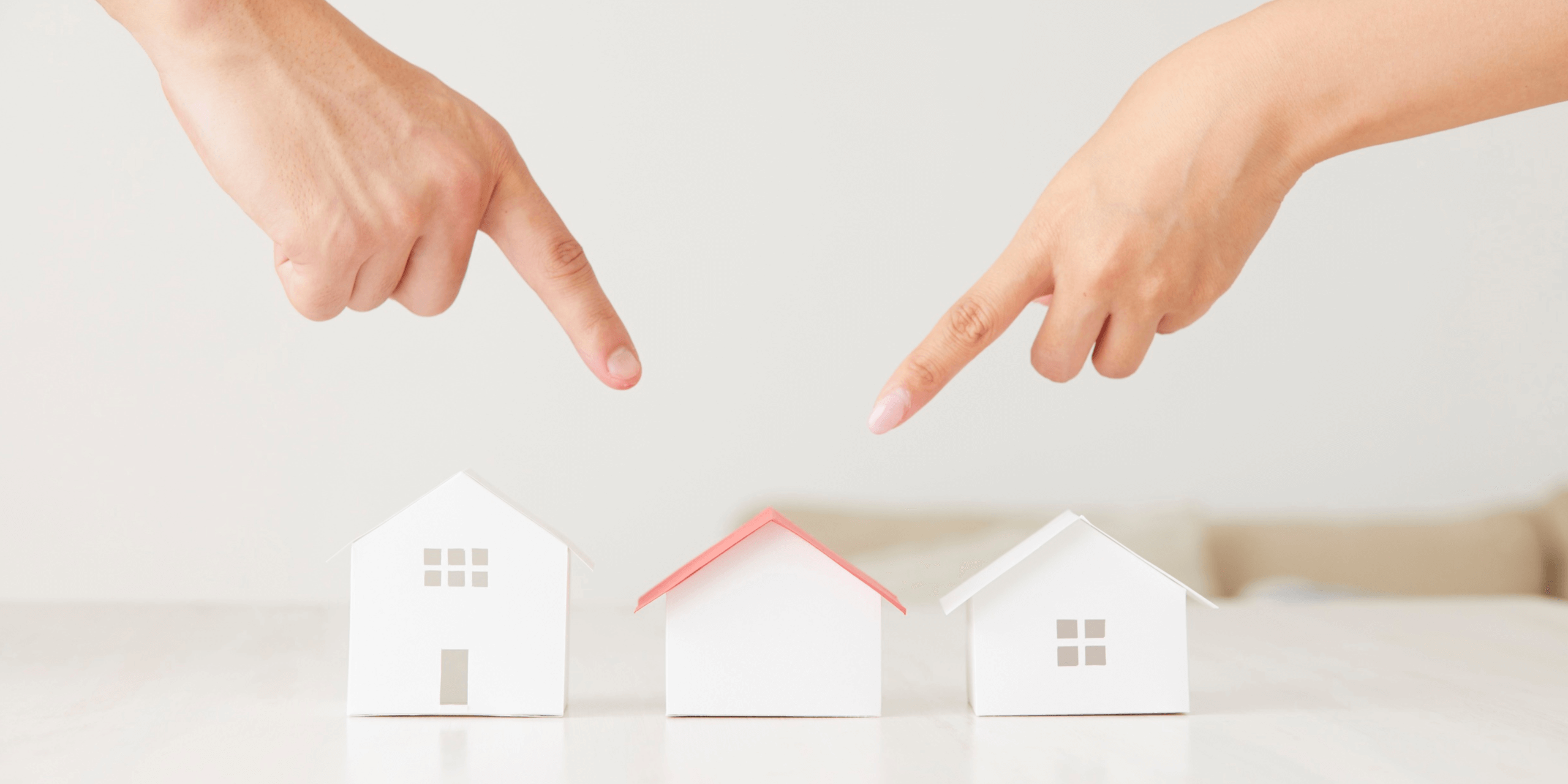 fingers pointing at figure house on desk